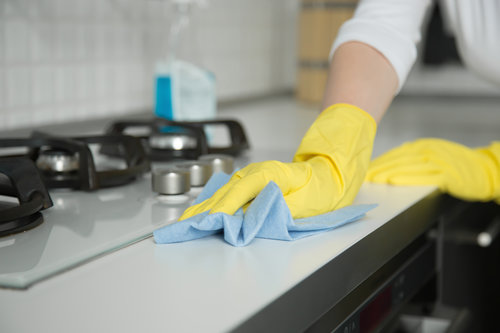 Closeup of female hands in rubber gloves cleaning the cooker